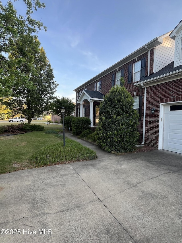 view of front of property with brick siding, a garage, driveway, and a front yard