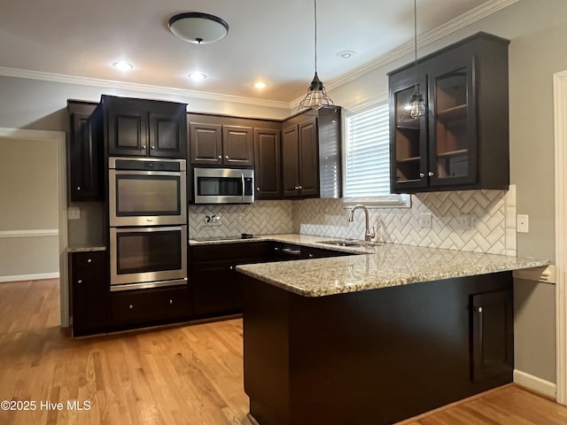 kitchen with backsplash, light stone countertops, a sink, a peninsula, and stainless steel appliances