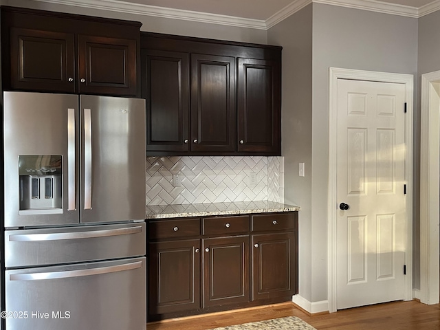 kitchen featuring crown molding, decorative backsplash, dark brown cabinets, stainless steel fridge with ice dispenser, and light wood finished floors