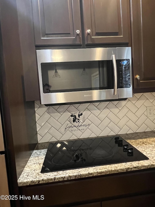 interior details featuring decorative backsplash, black electric cooktop, stainless steel microwave, and dark brown cabinetry