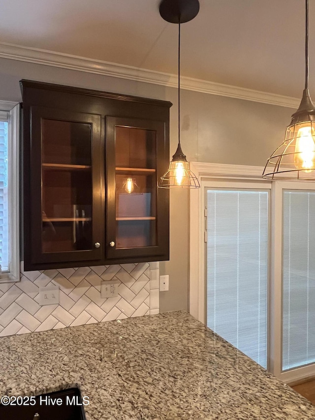 kitchen with hanging light fixtures, decorative backsplash, ornamental molding, and dark brown cabinetry