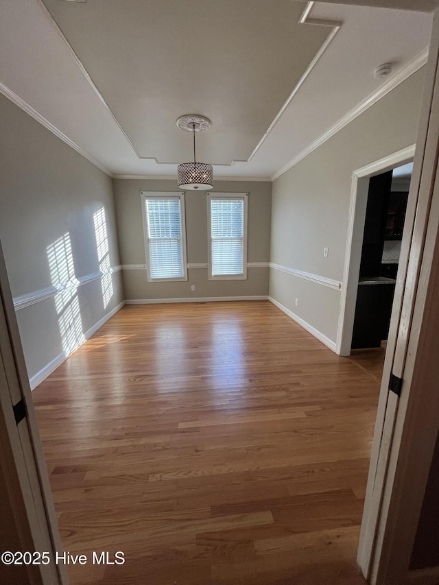 spare room featuring baseboards, ornamental molding, and light wood-type flooring