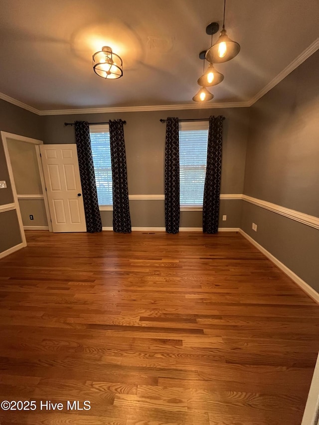 unfurnished room featuring crown molding, baseboards, and wood finished floors