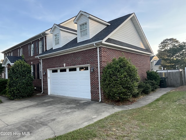 view of home's exterior featuring brick siding, a garage, fence, and driveway