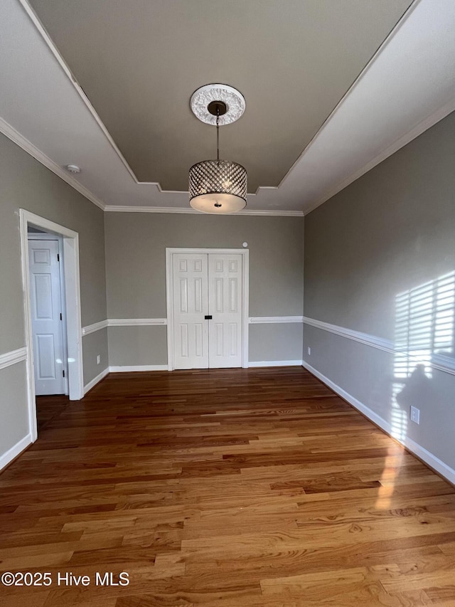 unfurnished dining area with baseboards, ornamental molding, and wood finished floors