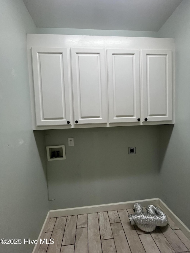 clothes washing area with cabinet space, hookup for a washing machine, electric dryer hookup, baseboards, and wood finished floors
