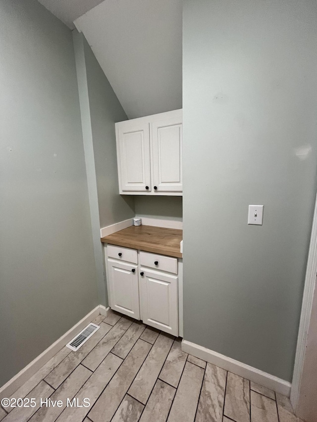 clothes washing area featuring baseboards, light wood-style flooring, and visible vents