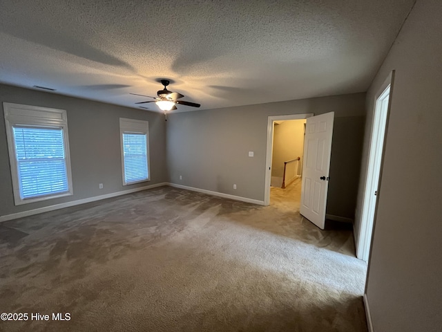 unfurnished bedroom with carpet flooring, a textured ceiling, a ceiling fan, baseboards, and visible vents