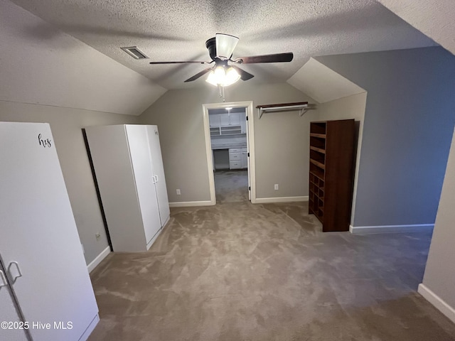 additional living space with ceiling fan, a textured ceiling, carpet, lofted ceiling, and visible vents