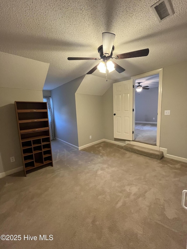 additional living space with visible vents, carpet flooring, a textured ceiling, and ceiling fan