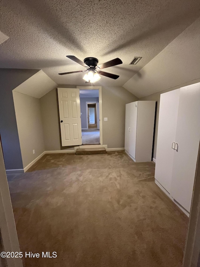 additional living space featuring visible vents, carpet flooring, a textured ceiling, and lofted ceiling