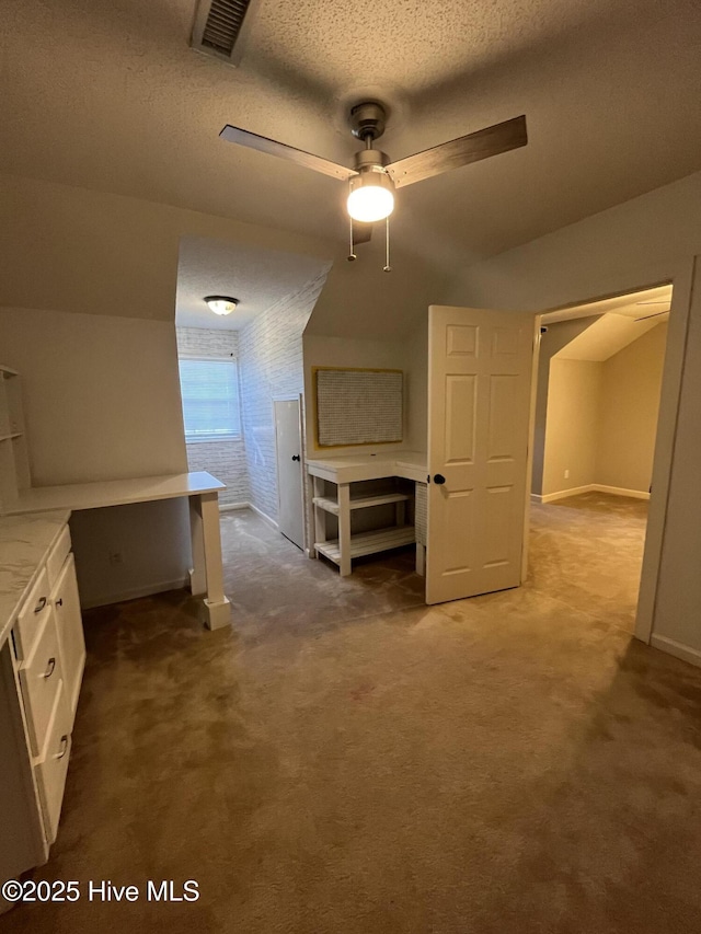 interior space with a textured ceiling, visible vents, baseboards, lofted ceiling, and carpet