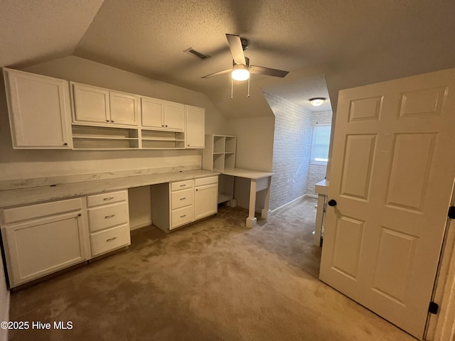 unfurnished office with visible vents, lofted ceiling, carpet flooring, a textured ceiling, and a ceiling fan