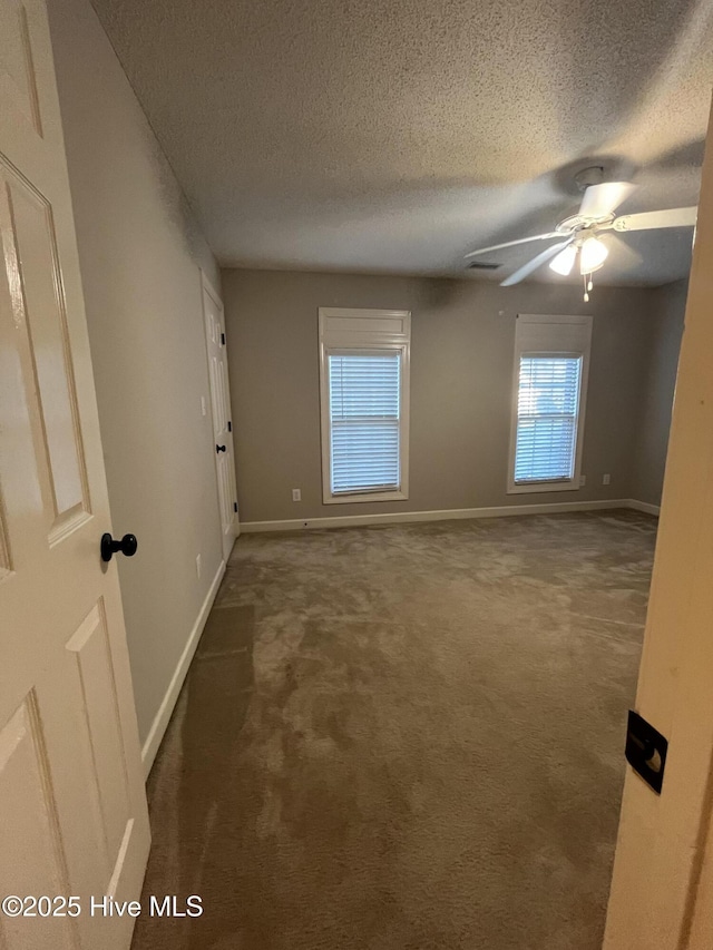 empty room with a ceiling fan, a textured ceiling, baseboards, and carpet