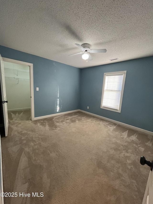 carpeted empty room featuring baseboards, a ceiling fan, and visible vents