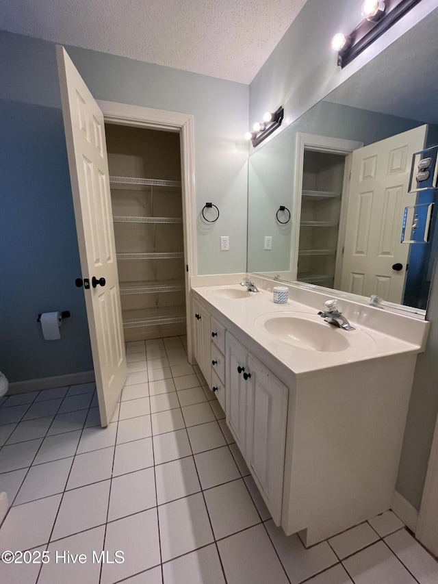 full bathroom with double vanity, tile patterned floors, and a sink