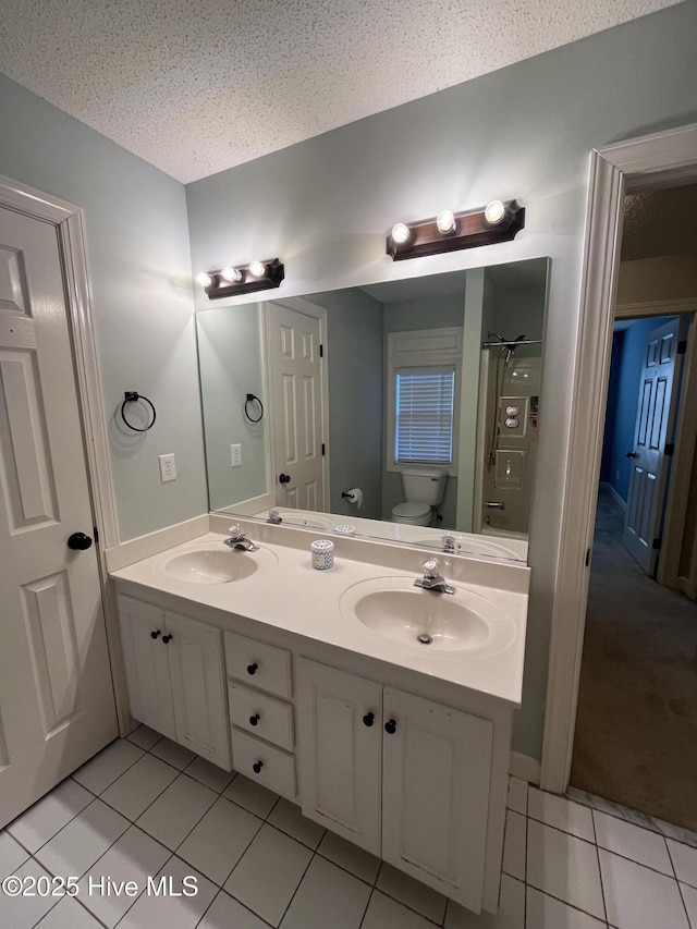 bathroom with toilet, a sink, and tile patterned flooring