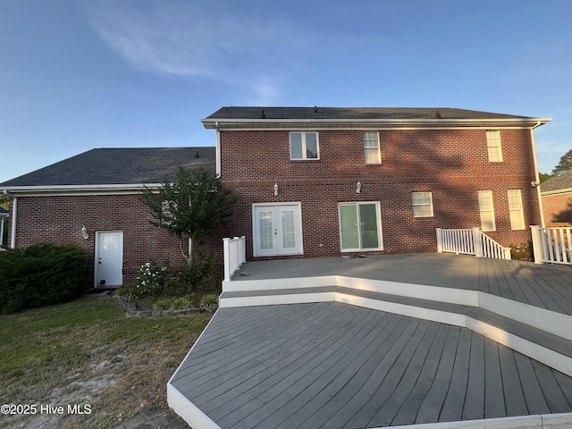 rear view of property featuring brick siding, french doors, and a deck