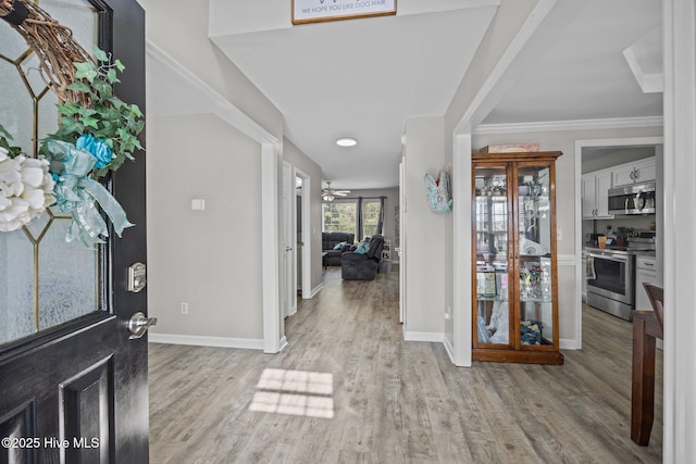 foyer featuring baseboards, ornamental molding, a ceiling fan, and wood finished floors