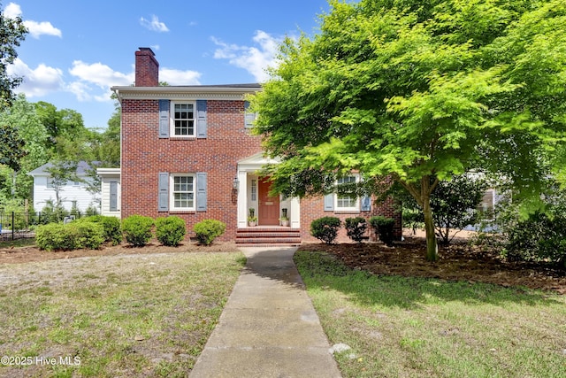 2405 Oleander Dr, Wilmington, NC 28403 - colonial house with a chimney, brick siding, fence, and a front yard