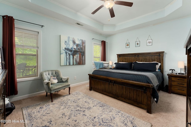 carpeted bedroom with a raised ceiling, visible vents, crown molding, and baseboards