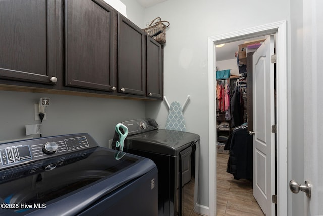 washroom with light wood-type flooring, cabinet space, and washing machine and clothes dryer