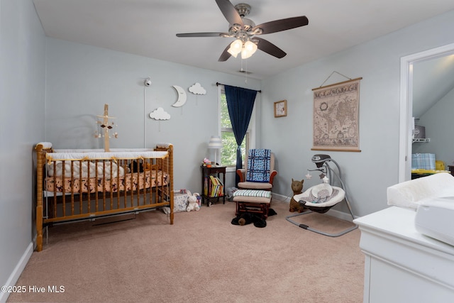 carpeted bedroom with a crib and ceiling fan