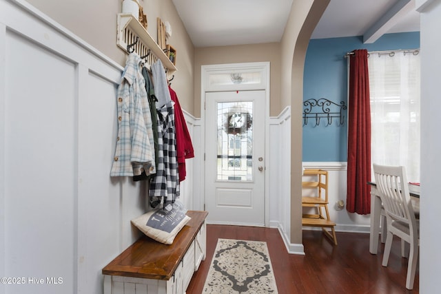 entryway with arched walkways, wainscoting, and wood finished floors