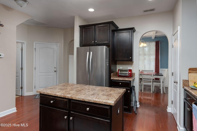 kitchen featuring dark wood-style floors, arched walkways, and freestanding refrigerator