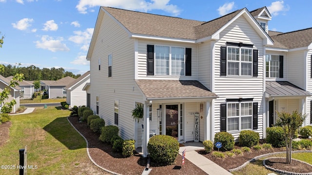 view of front facade featuring roof with shingles and a front yard