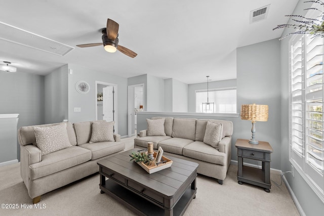 living area with ceiling fan, light colored carpet, attic access, baseboards, and visible vents