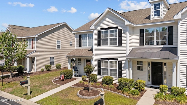 view of front facade with a shingled roof, a front lawn, metal roof, and a standing seam roof