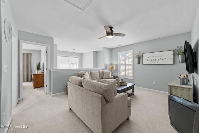 living room featuring baseboards, ceiling fan, light carpet, and attic access