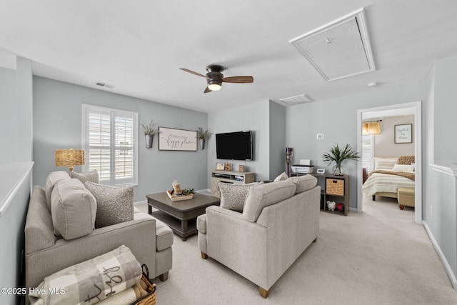 living room with light carpet, a ceiling fan, attic access, and visible vents