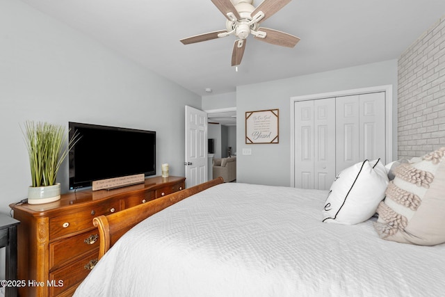 bedroom featuring ceiling fan, brick wall, and a closet