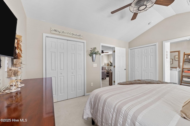 bedroom featuring multiple closets, lofted ceiling, connected bathroom, a ceiling fan, and carpet