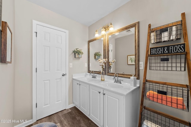 full bathroom with double vanity, visible vents, a sink, and wood finished floors