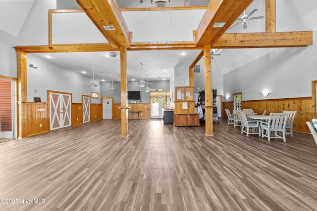 living area featuring a wainscoted wall, a ceiling fan, and high vaulted ceiling