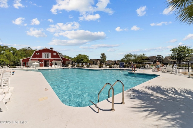 pool featuring fence, a barn, and a patio area