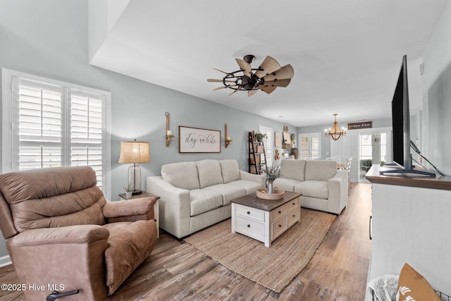 living area featuring ceiling fan with notable chandelier and light wood finished floors
