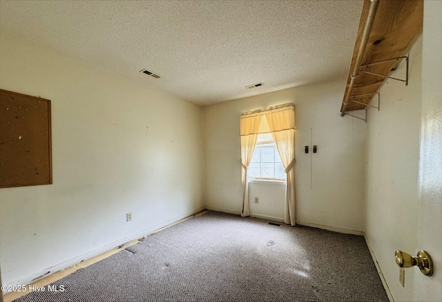 carpeted empty room with a textured ceiling, baseboards, and visible vents