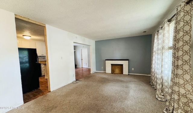 unfurnished living room featuring baseboards, carpet floors, a brick fireplace, and a textured ceiling