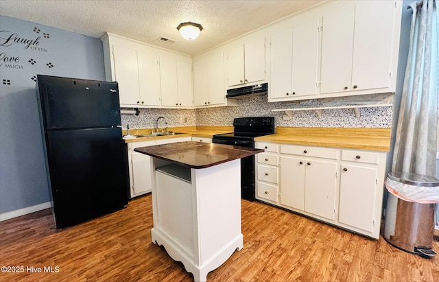 kitchen with light wood-type flooring, black appliances, visible vents, and under cabinet range hood