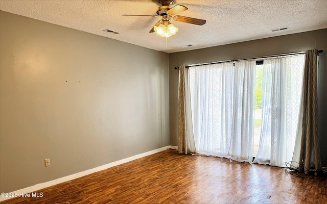 unfurnished room with ceiling fan, a textured ceiling, visible vents, and wood finished floors
