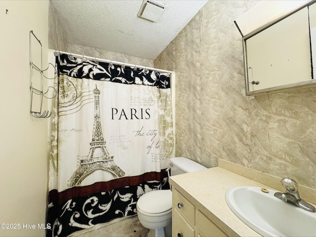 bathroom with toilet, a textured ceiling, curtained shower, visible vents, and vanity