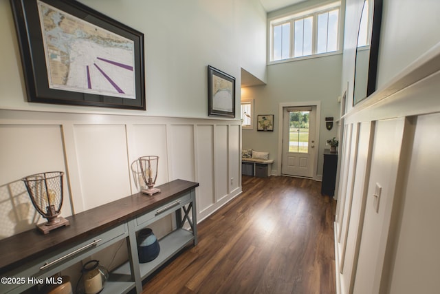 596 W Burton Farm Dr, Minnesott Beach, NC 28510 - doorway featuring dark wood-style flooring, a wainscoted wall, a decorative wall, and a towering ceiling