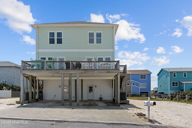 view of front of house with a wooden deck, driveway, central AC, and fence