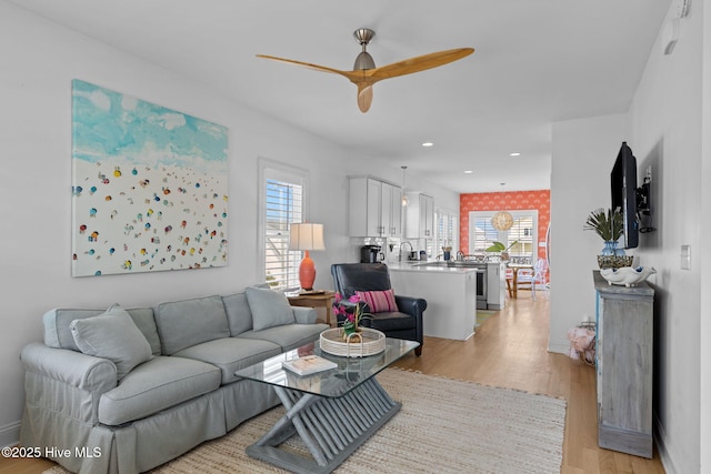 living area with a ceiling fan, plenty of natural light, light wood-type flooring, and recessed lighting