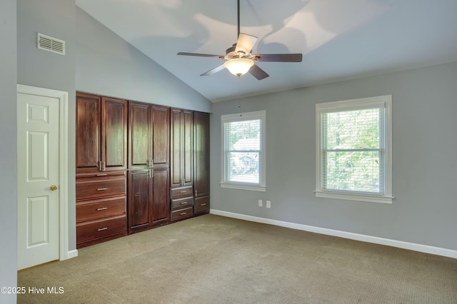 unfurnished bedroom with ceiling fan, light colored carpet, baseboards, vaulted ceiling, and visible vents