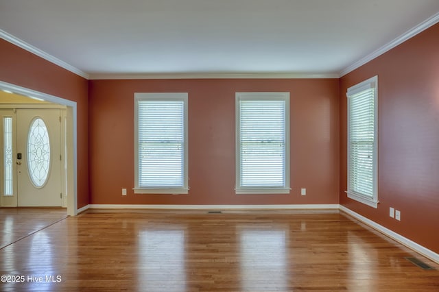 foyer entrance with baseboards, visible vents, plenty of natural light, and wood finished floors